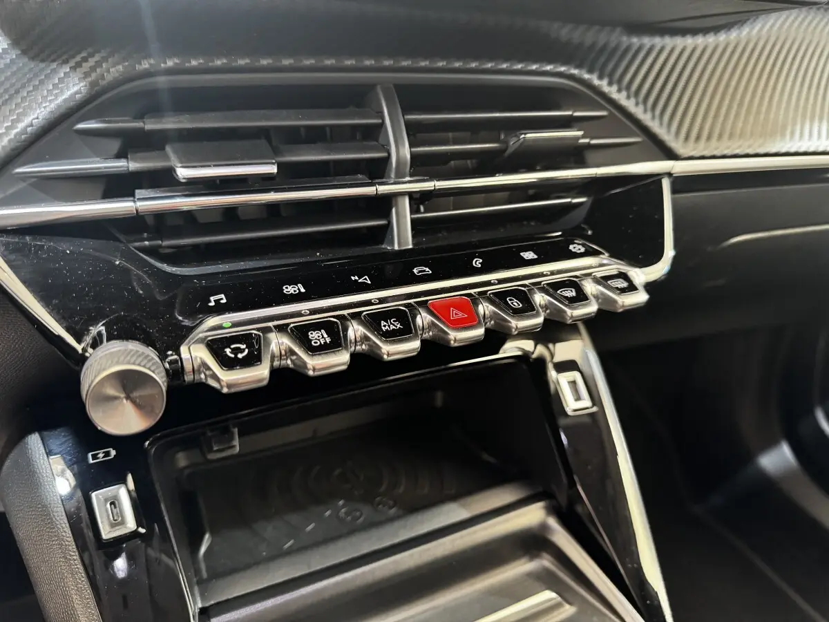 Vue rapprochée de la console centrale noire du Peugeot 2008 avec boutons chrome et écran tactile intégré.