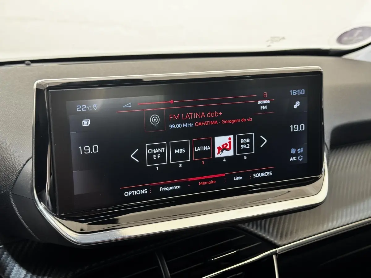 Écran tactile central de la Peugeot 2008 blanc, affichant la radio FM Latina avec interface moderne et bordure chromée.