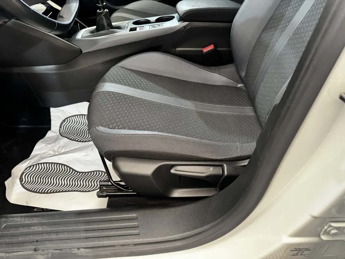 Vue rapprochée du siège avant droit gris foncé de la Peugeot 2008 blanche, avec levier de réglage manuel visible.