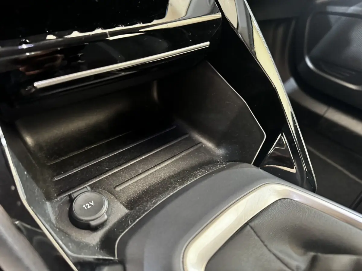 Gros plan intérieur sur la console centrale noire du Peugeot 2008 avec prise 12V visible et finitions argentées.