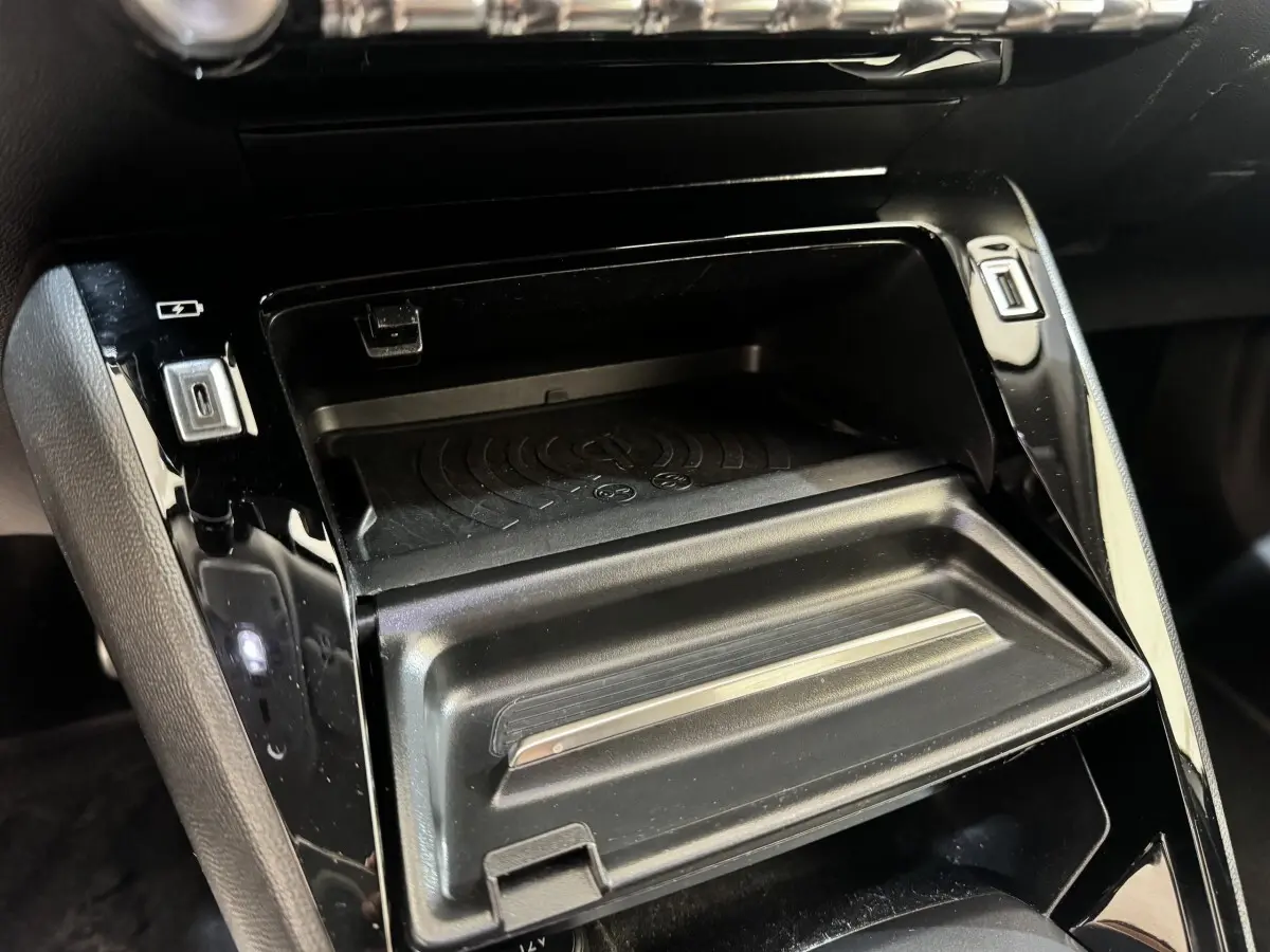 Gros plan intérieur sur la console centrale noire du Peugeot 2008, avec compartiment de rangement et ports USB visibles.