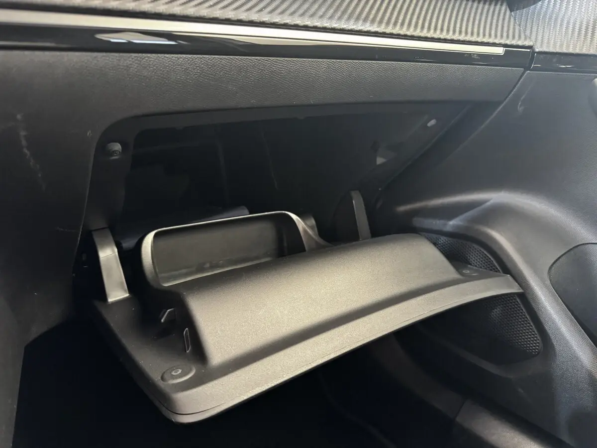 Gros plan sur la boîte à gants ouverte côté passager de l'intérieur noir du Peugeot 2008 blanc.