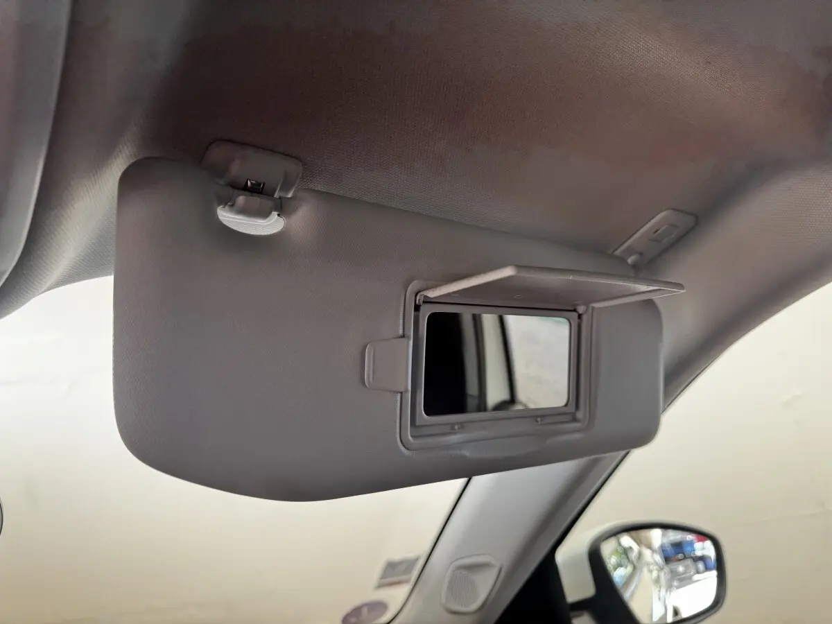 Détail du pare-soleil côté conducteur avec miroir de courtoisie ouvert dans l'habitacle blanc du Peugeot 2008.