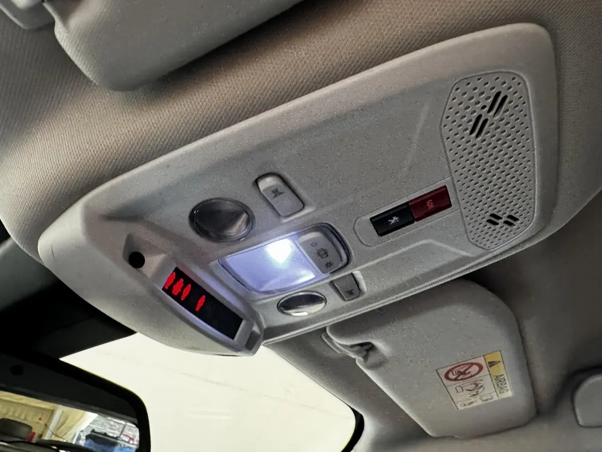 Plafonnier intérieur avec commandes lumineuses et bouton d'appel d'urgence dans un Peugeot 2008 blanc, vue en léger contre-plongée.