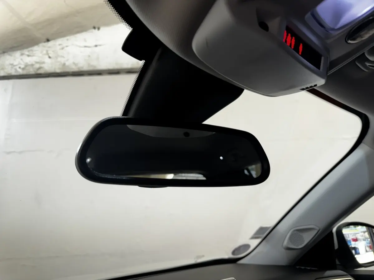 Rétroviseur intérieur noir du Peugeot 2008 blanc, vue depuis l'habitacle côté conducteur, avec pare-brise et rétroviseur extérieur visibles.