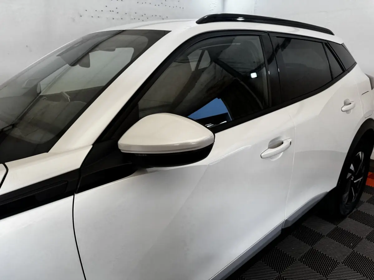 Vue de profil côté gauche du Peugeot 2008 blanc avec rétroviseur assorti et vitres teintées.