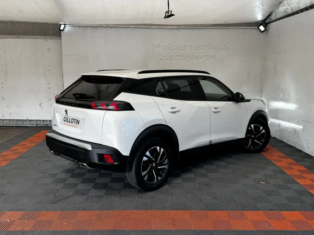 Peugeot 2008 blanc en 3/4 arrière droit, toit noir, feux arrière à LED et jantes alliage bicolores.