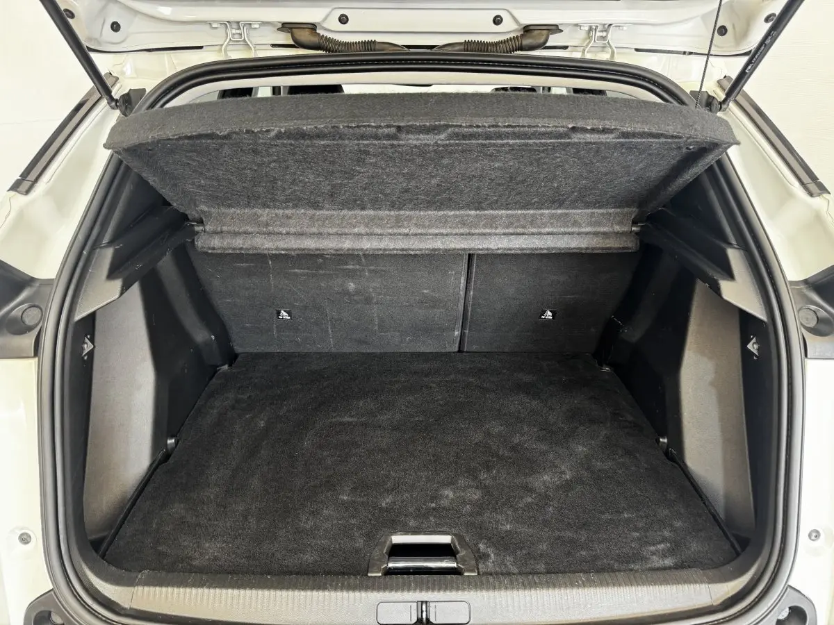 Coffre ouvert de Peugeot 2008 blanc, vue arrière montrant l'espace de chargement avec tablette de séparation relevée.