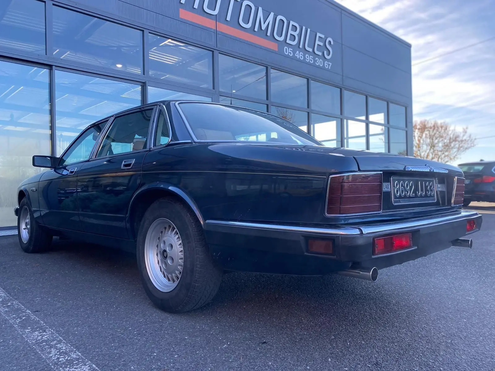 Jaguar XJ6 3.6 Sovereign bleu vue 3/4 arrière droit, avec feux arrière rectangulaires et double sortie d'échappement.