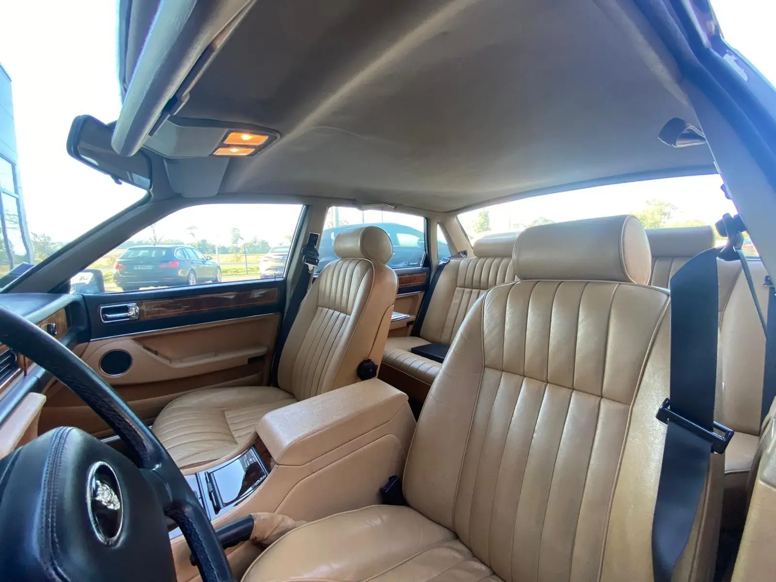Intérieur beige cuir de la Jaguar XJ6 3.6 Sovereign 1987, vue côté conducteur avec planche de bord en bois.