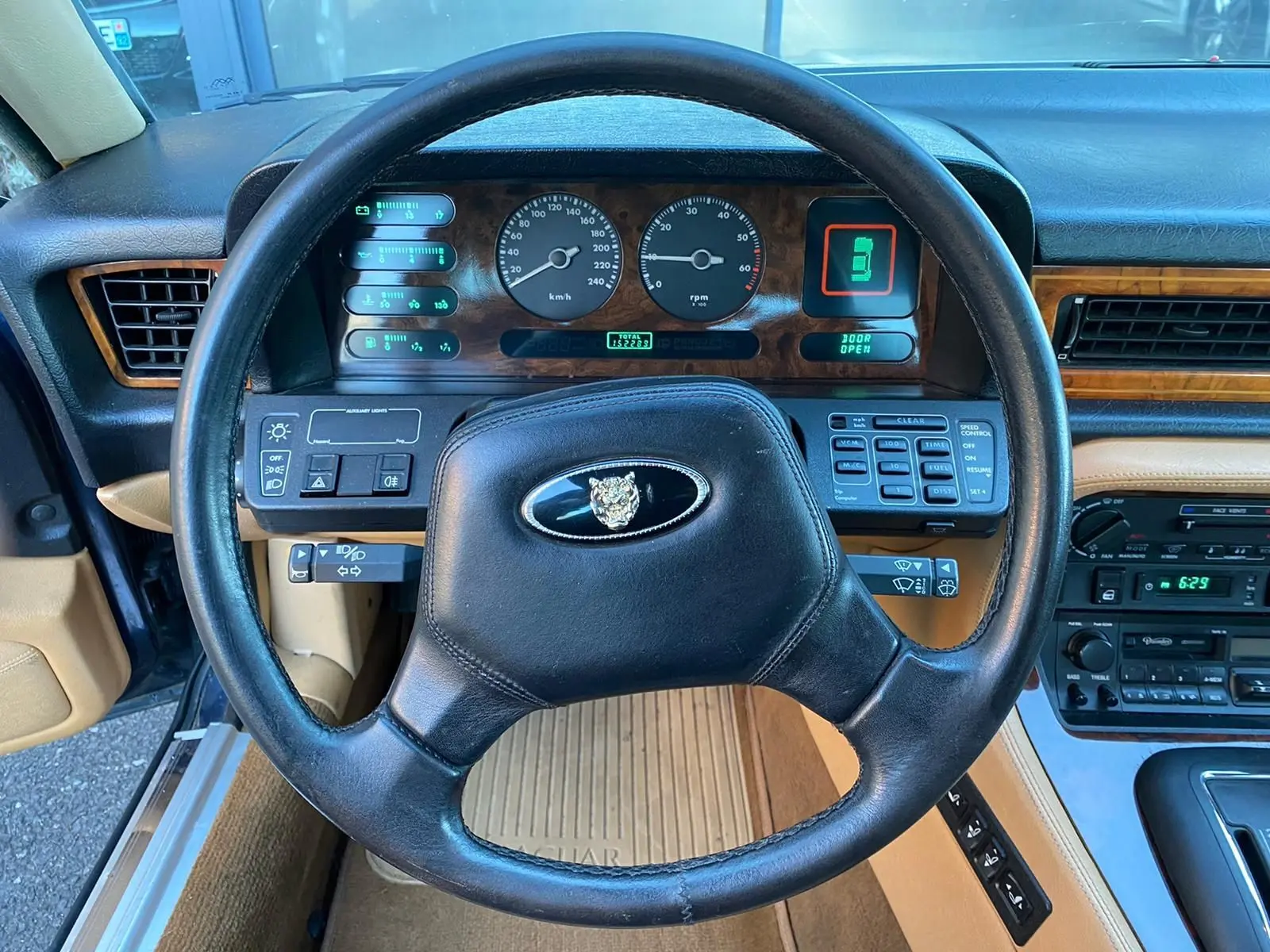 Vue intérieure centrée sur le volant noir et le tableau de bord en bois d'une Jaguar XJ6 3.6 Sovereign bleu de 1987.
