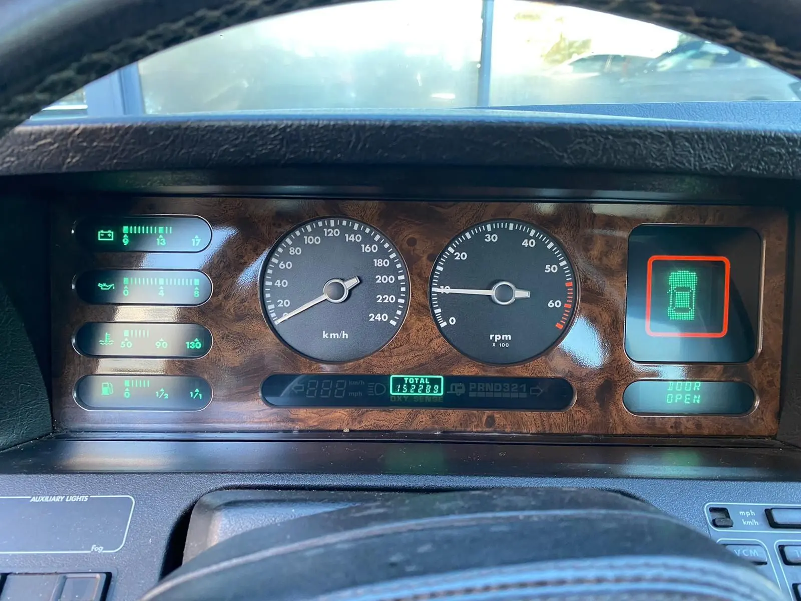 Tableau de bord en bois du Jaguar XJ6 3.6 Sovereign 1987, affichage digital et compteurs ronds vus de face.