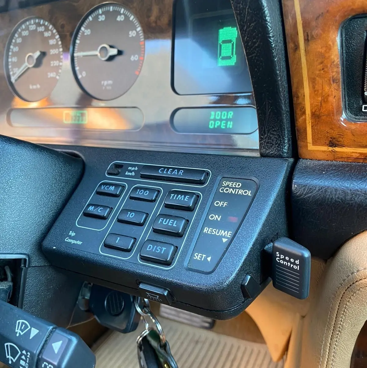 Gros plan sur le tableau de bord en bois et les commandes du cruise control d'une Jaguar XJ6 3.6 Sovereign bleu de 1987