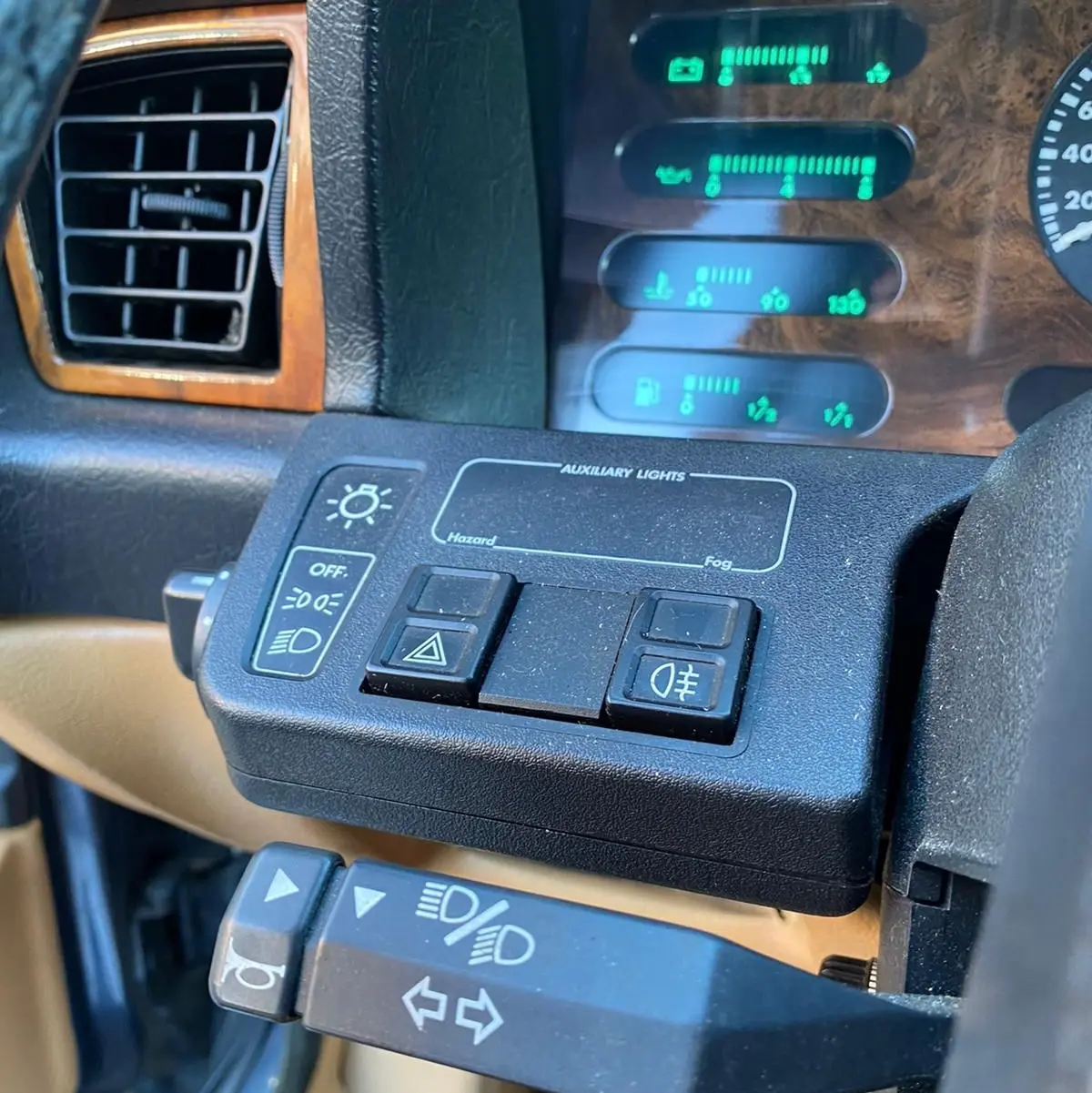 Gros plan sur le tableau de bord de la Jaguar XJ6 3.6 Sovereign 1987, avec commandes d'éclairage et bois verni.