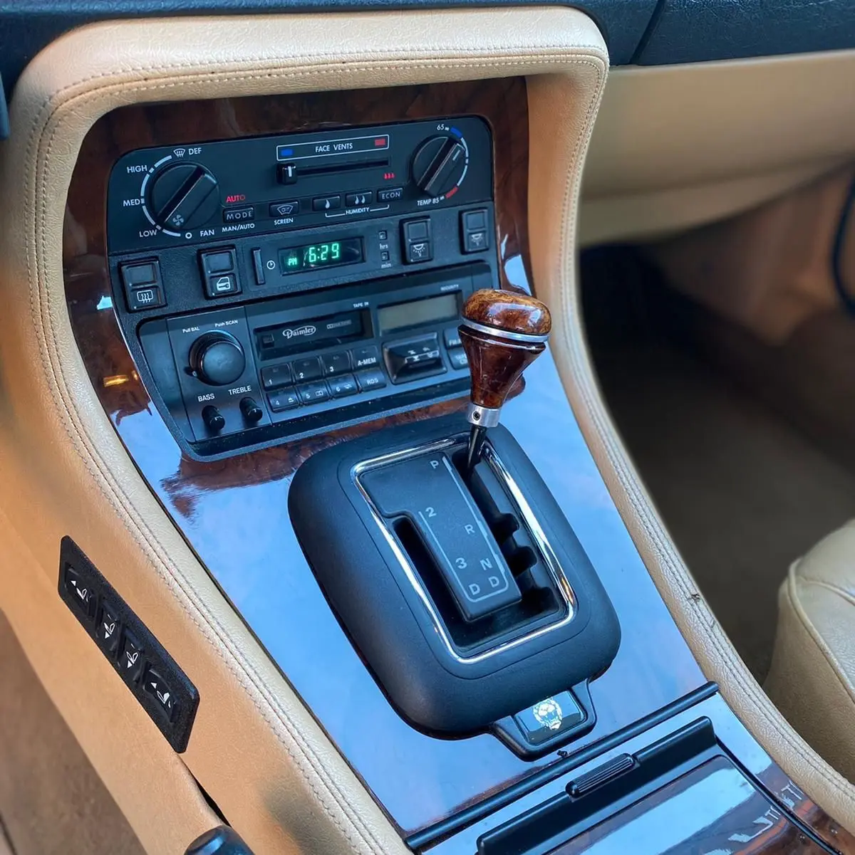 Gros plan sur la console centrale beige avec levier de vitesses bois et commandes d’origine d’une Jaguar XJ6 3.6 Sovereign 1987.