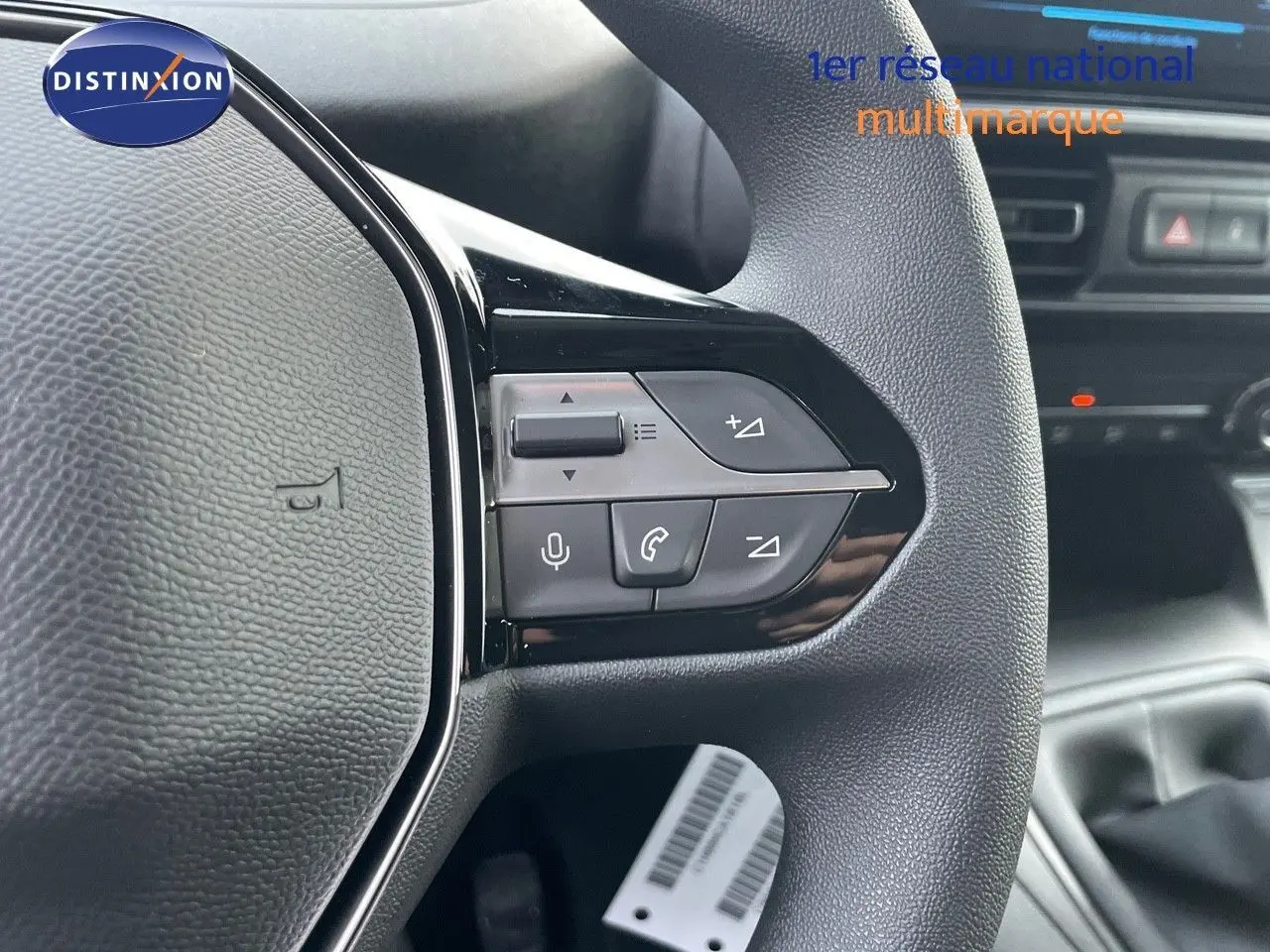 Gros plan sur les commandes du volant côté gauche du Peugeot Partner 2025, intérieur noir avec détails argentés.