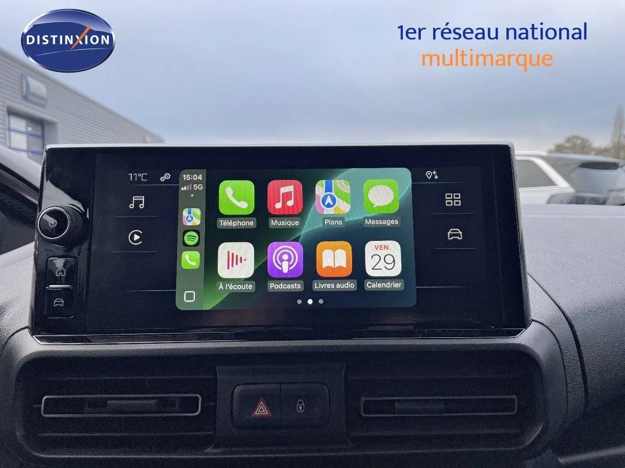 Écran tactile central du Peugeot Partner 2025, affichant les applications connectées, avec vue sur la planche de bord noire.