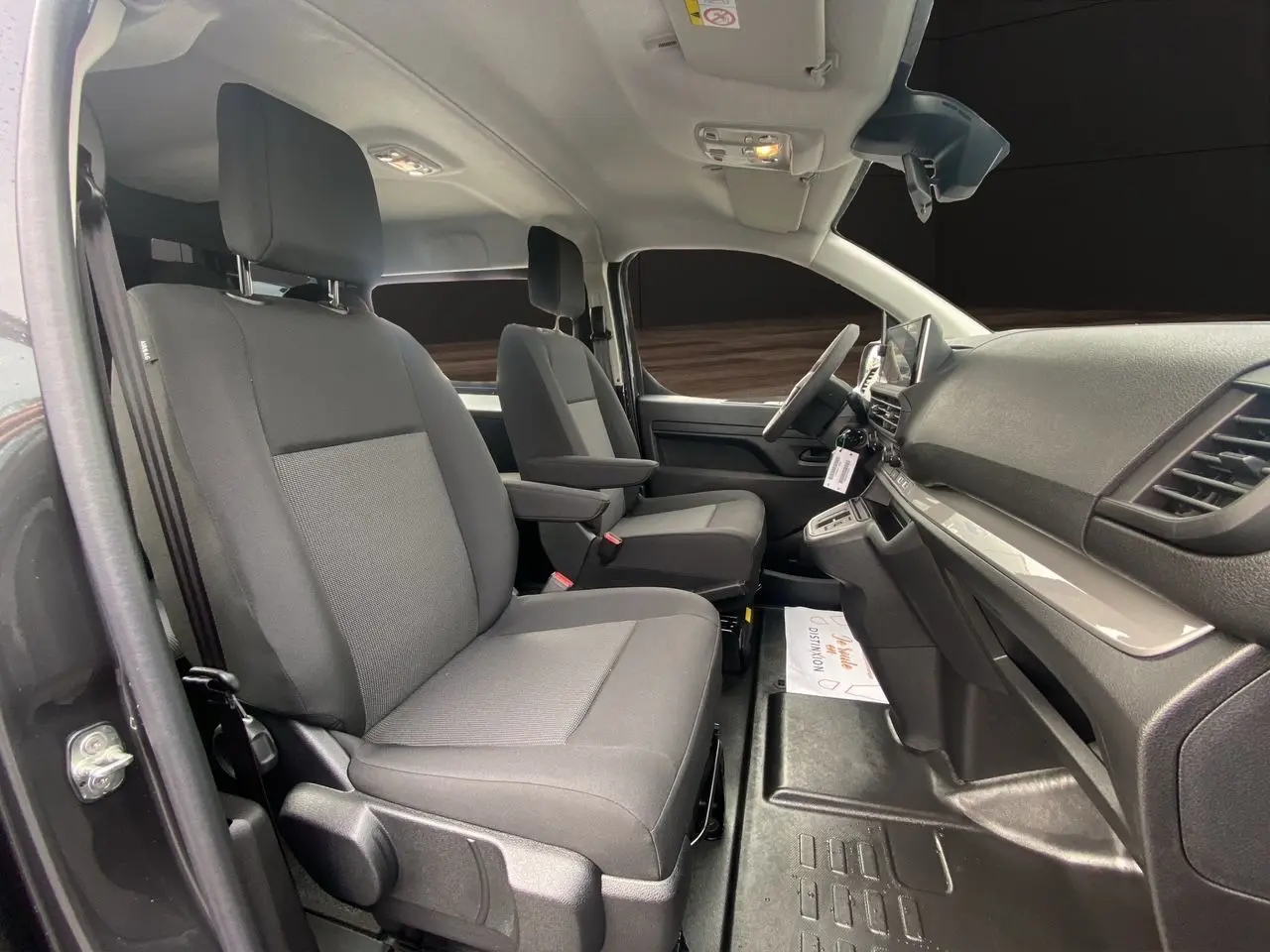 Vue intérieure côté gauche du Peugeot Expert cabine approfondie 2025, sièges tissu noir et planche de bord grise.