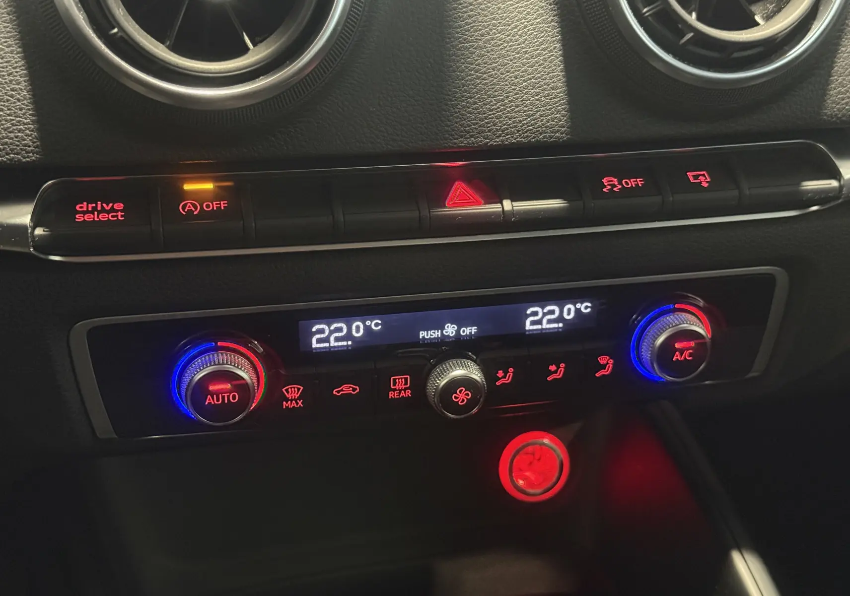 Vue rapprochée du tableau de bord de l'Audi A3 Sportback 2015 blanc, montrant la climatisation automatique et les commandes éclairées.