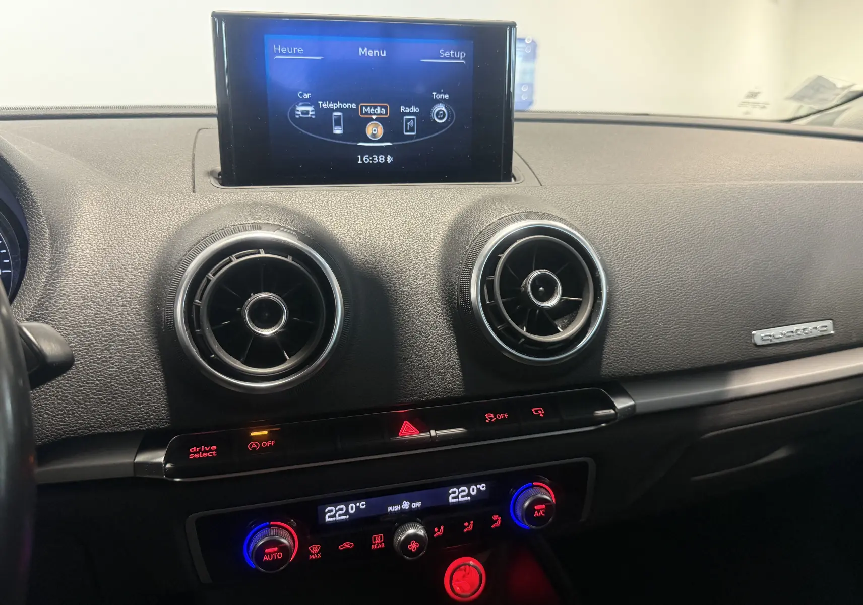 Vue intérieure du tableau de bord de l'Audi A3 Sportback 2015, avec écran multimédia et commandes climatisation rétroéclairées.