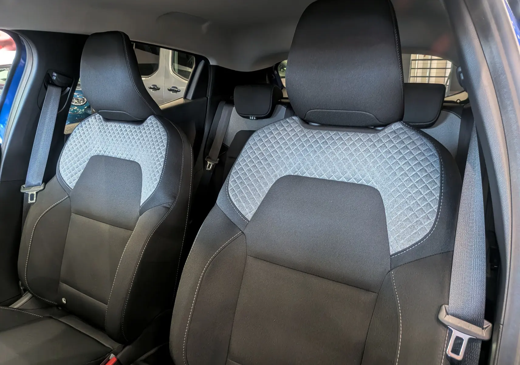 Vue intérieure rapprochée des sièges avant en tissu noir et gris avec surpiqûres, Renault Clio V Bleu Iron 2025.