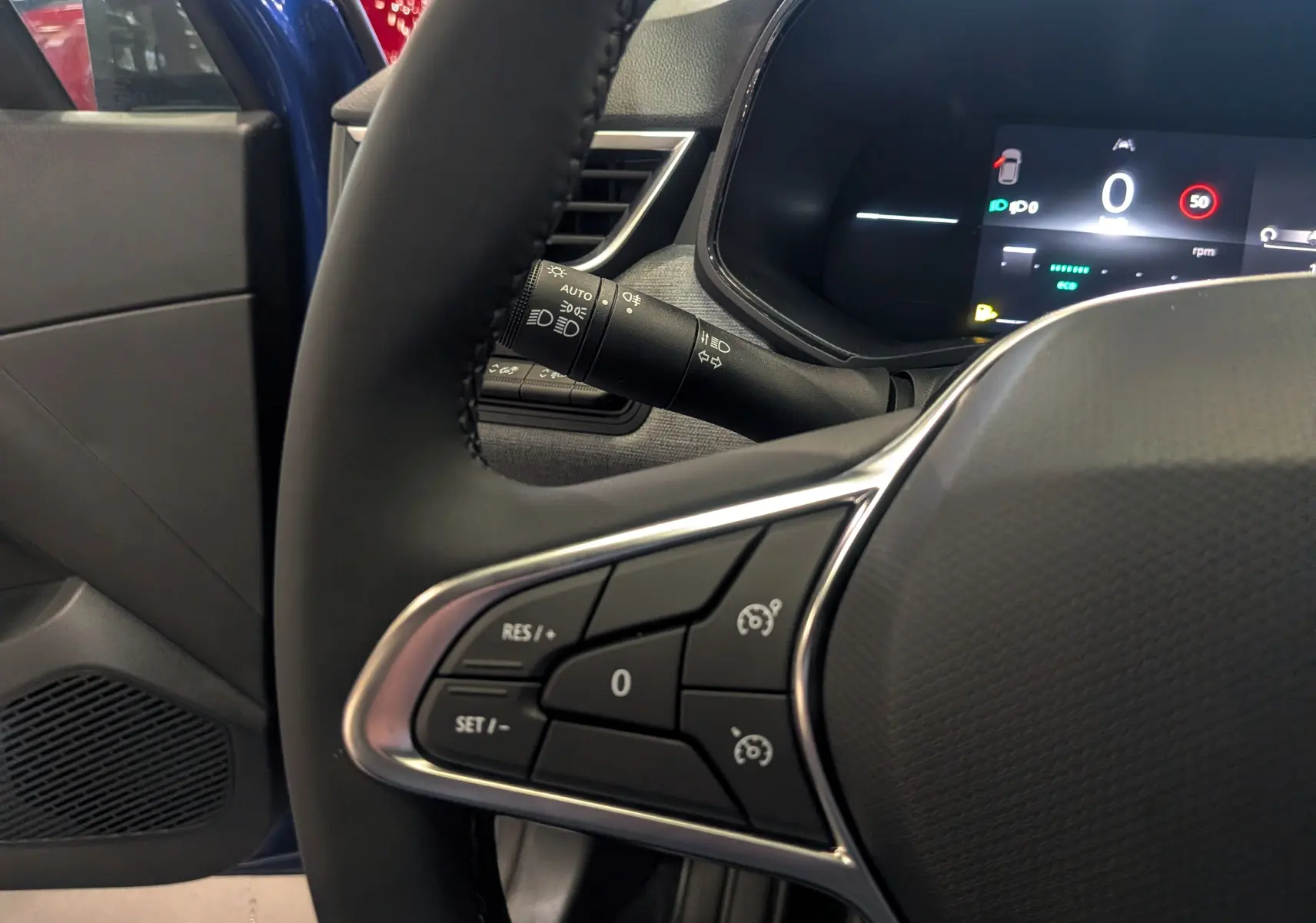 Détail du volant avec commandes intégrées et tableau de bord numérique, intérieur de Renault Clio V Bleu Iron, côté conducteur.