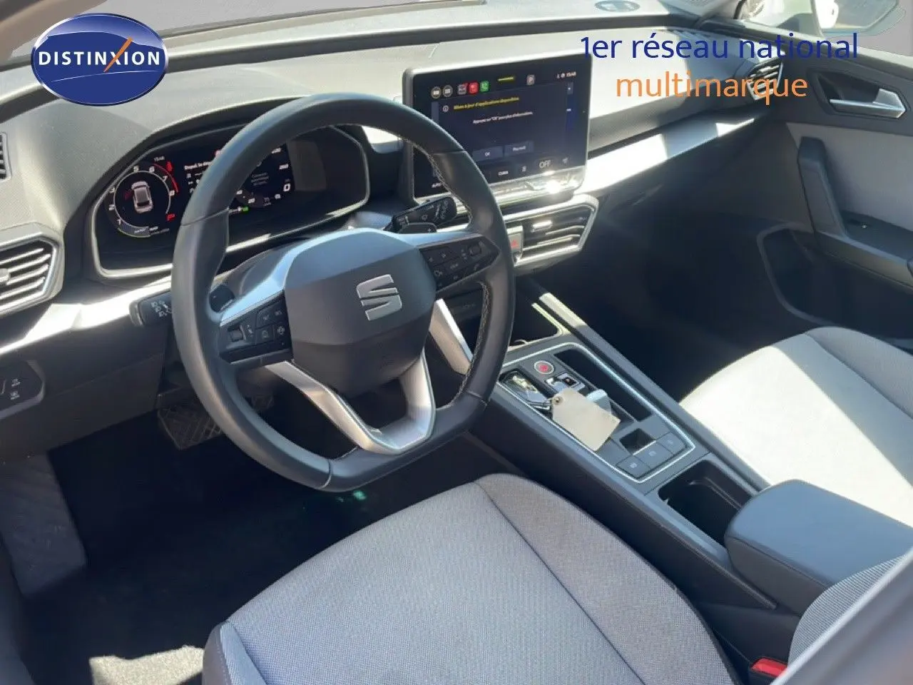 Vue intérieure côté conducteur du tableau de bord et volant cuir noir de la SEAT LEON 2025 blanc, avec écran tactile central.