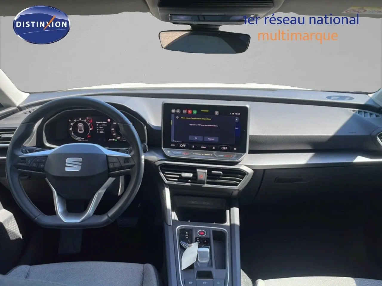 Vue intérieure avant du tableau de bord et volant noir du SEAT LEON blanc 2025 avec écran tactile central et boîte auto.