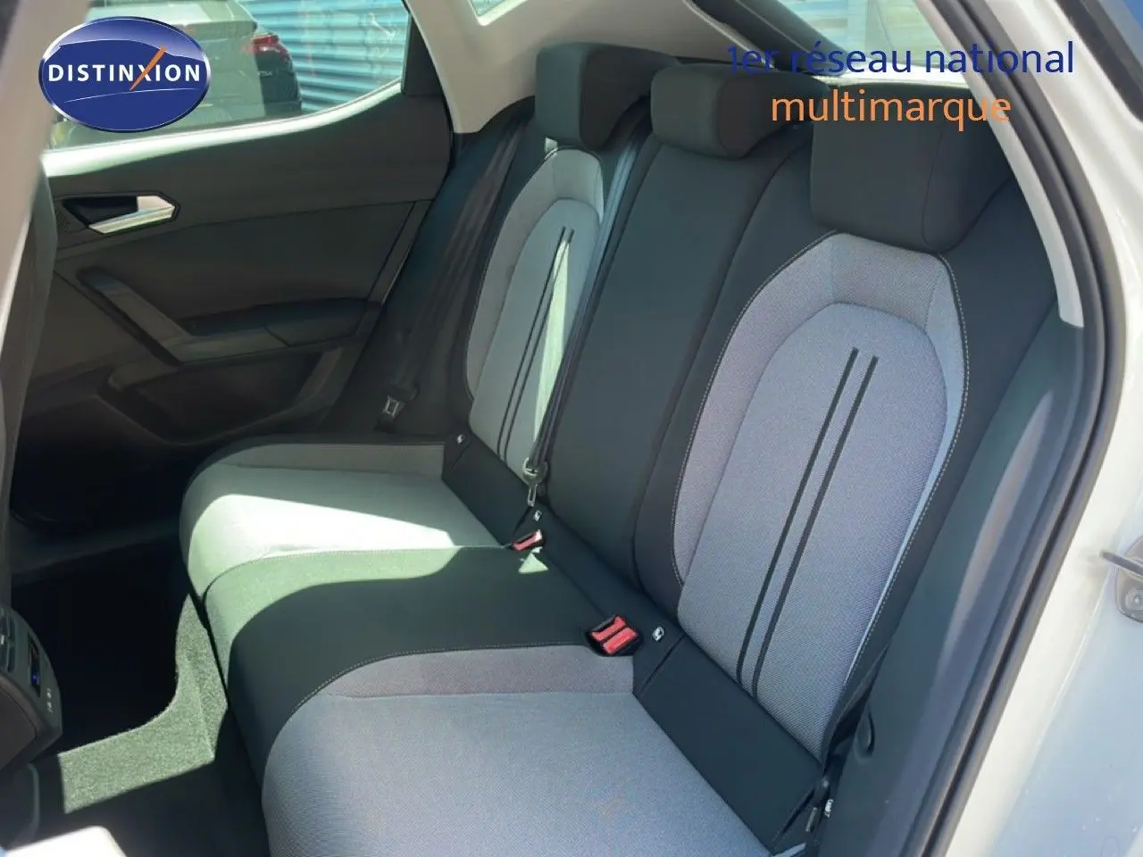 Vue intérieure sur les sièges arrière gris et noirs d’une SEAT LEON blanche, porte arrière droite ouverte.