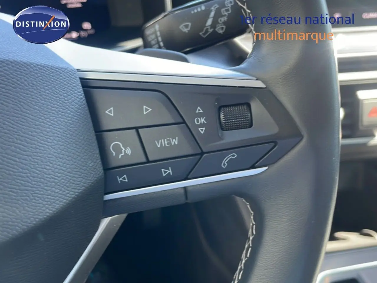 Gros plan sur les commandes au volant en cuir noir du SEAT Leon 1.5 TSI blanc, version 25e anniversaire.