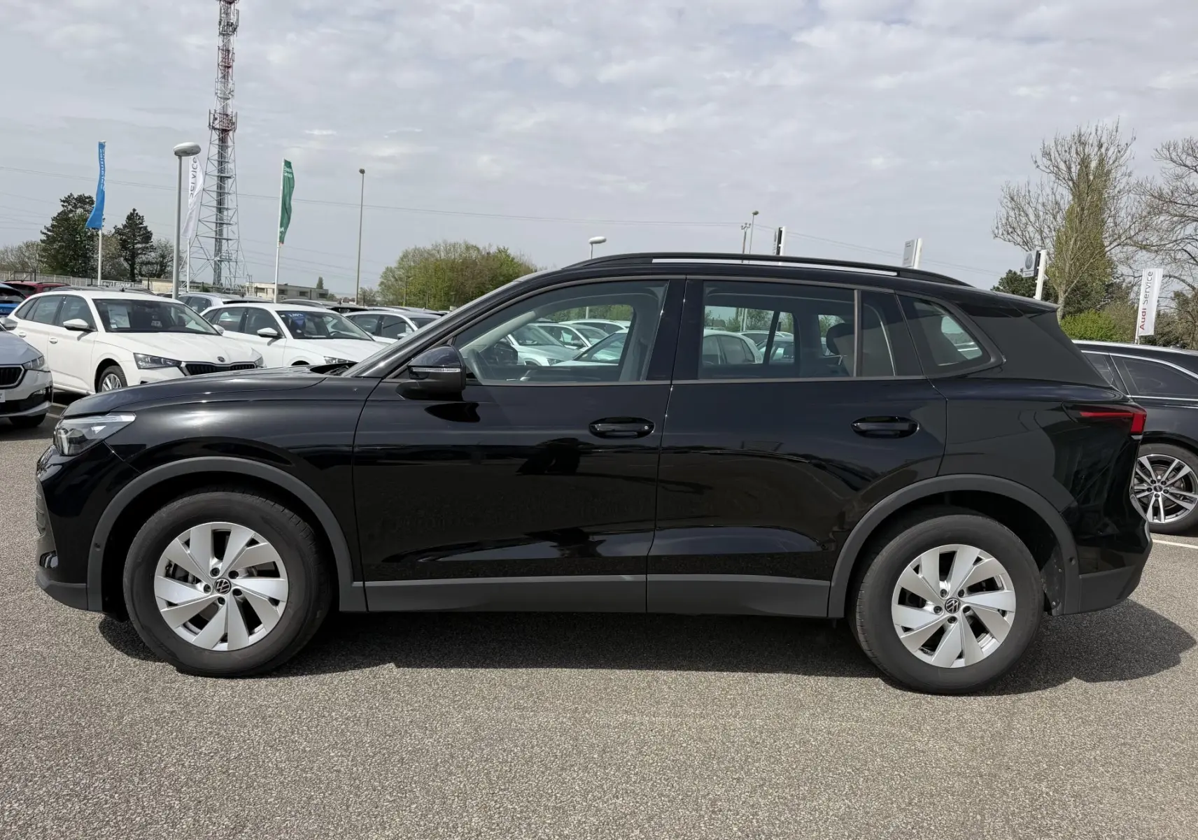 Profil droit d'un Volkswagen Tiguan noir 2025 garé en extérieur, avec jantes alliage légères et lignes épurées.