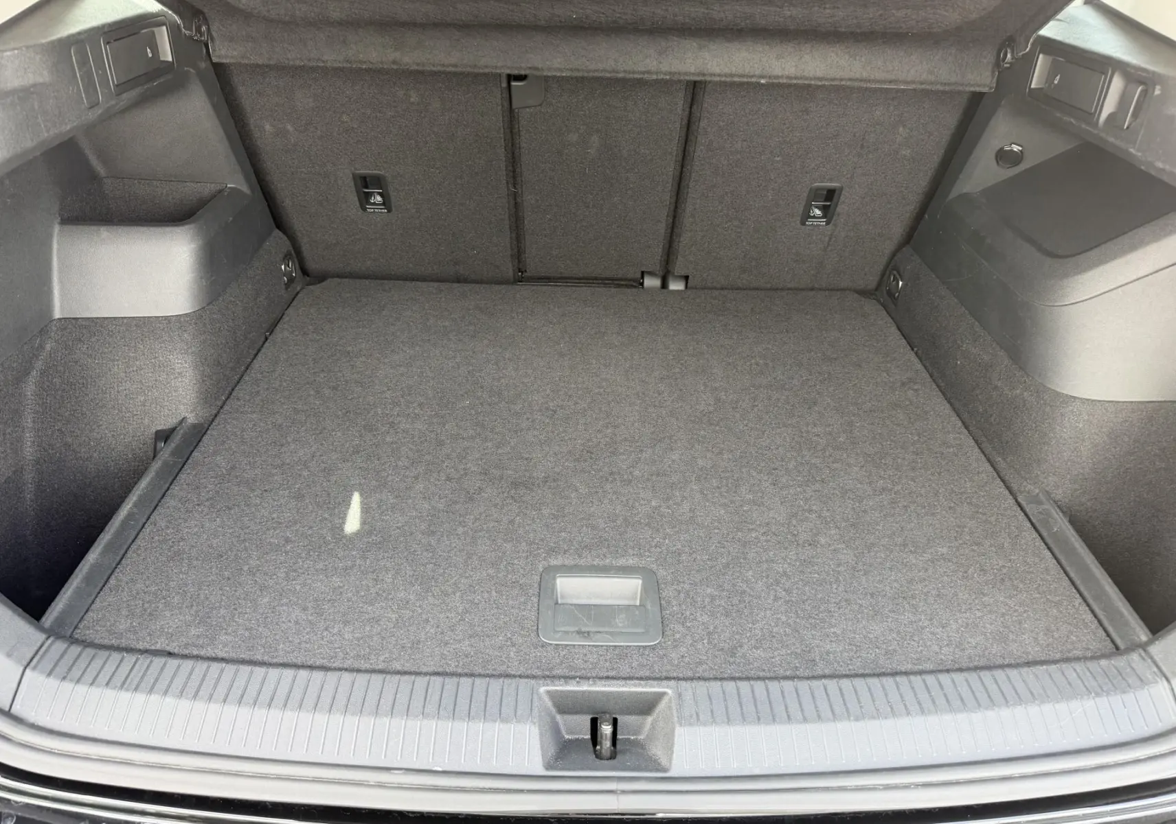 Coffre ouvert du Volkswagen Tiguan noir, vue de dessus montrant un espace de chargement propre et bien agencé.