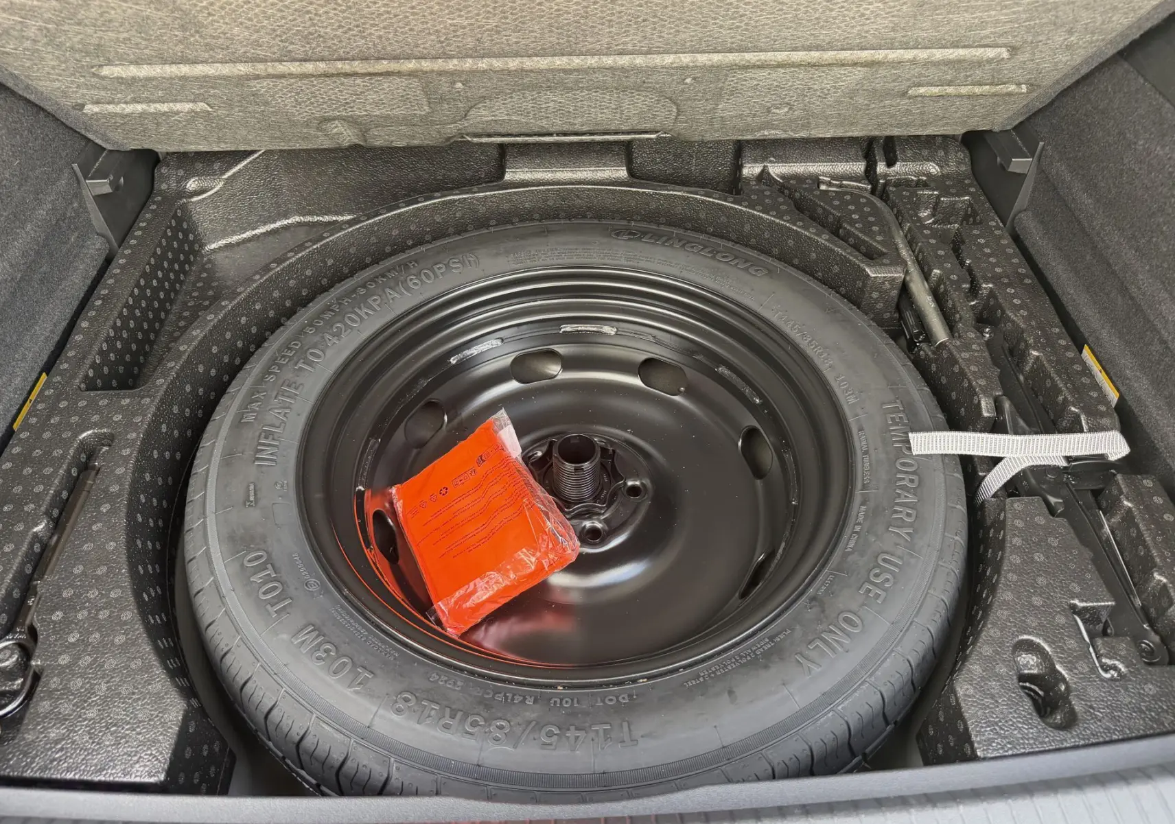 Gros plan sur la roue de secours compacte noire dans le coffre du Volkswagen Tiguan 2025, entourée de son rangement en mousse.