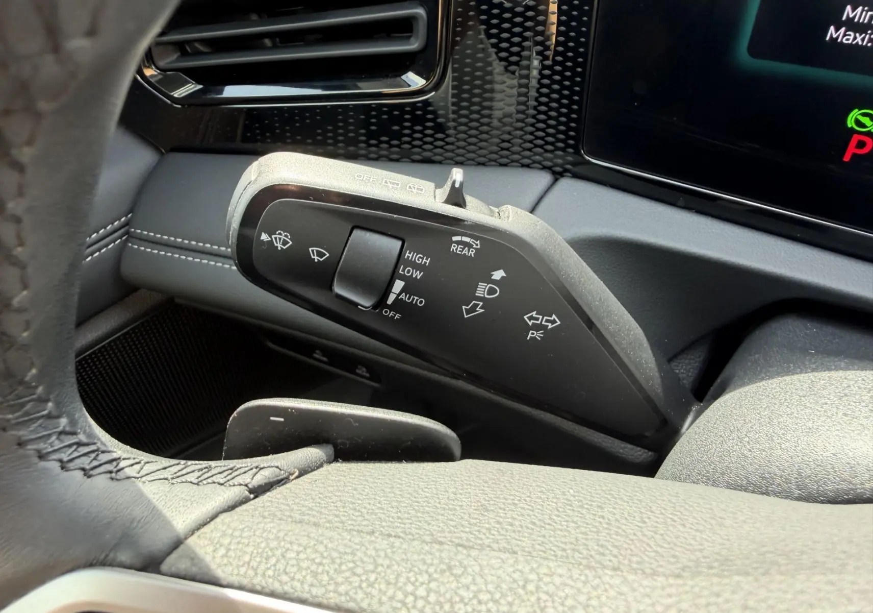 Gros plan sur la manette de commandes des essuie-glaces et feux du Volkswagen Tiguan 2025, intérieur noir avec coutures blanches.