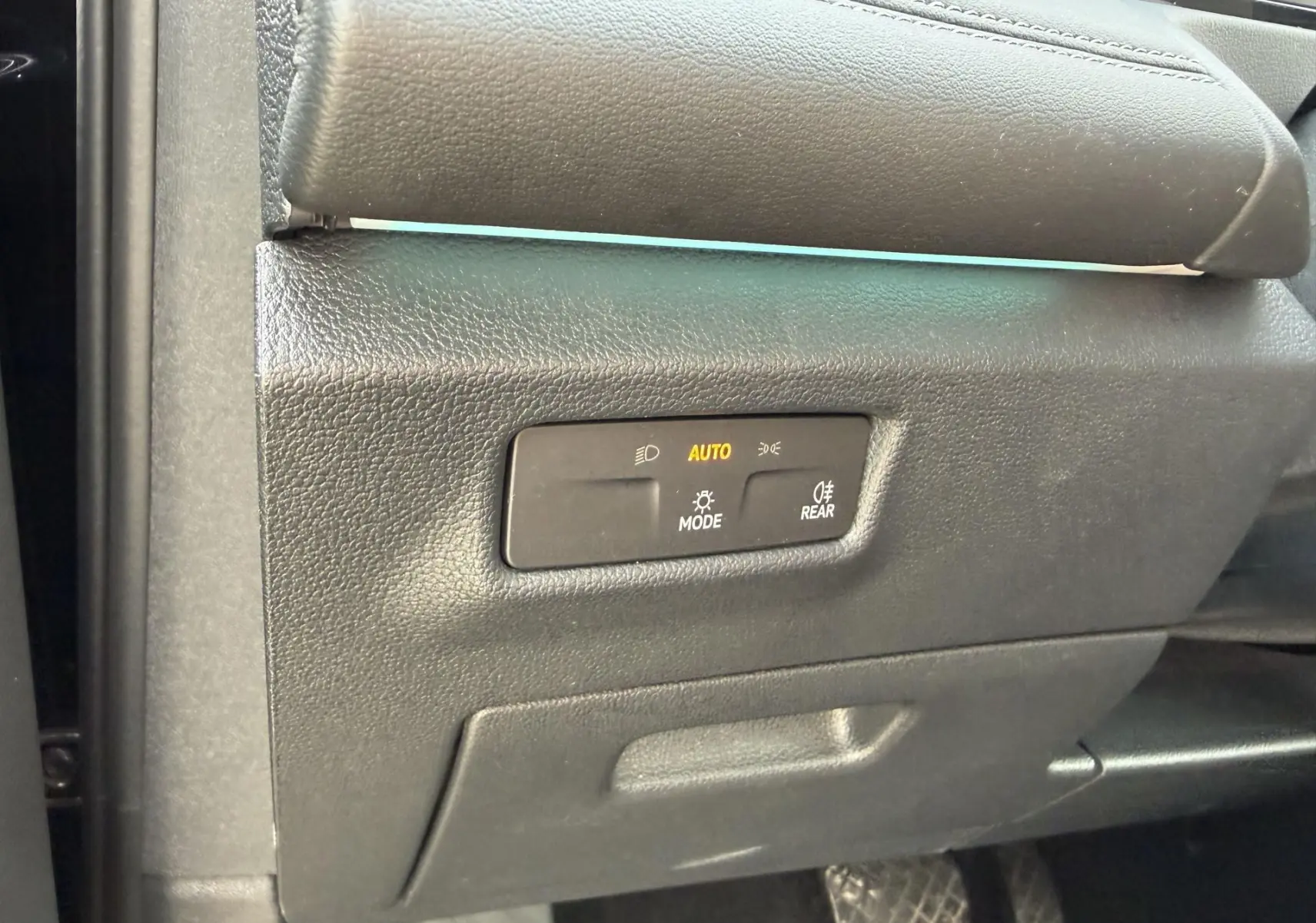Gros plan sur le panneau de commande des feux avec mode automatique, à l'intérieur du Volkswagen Tiguan noir 2025.