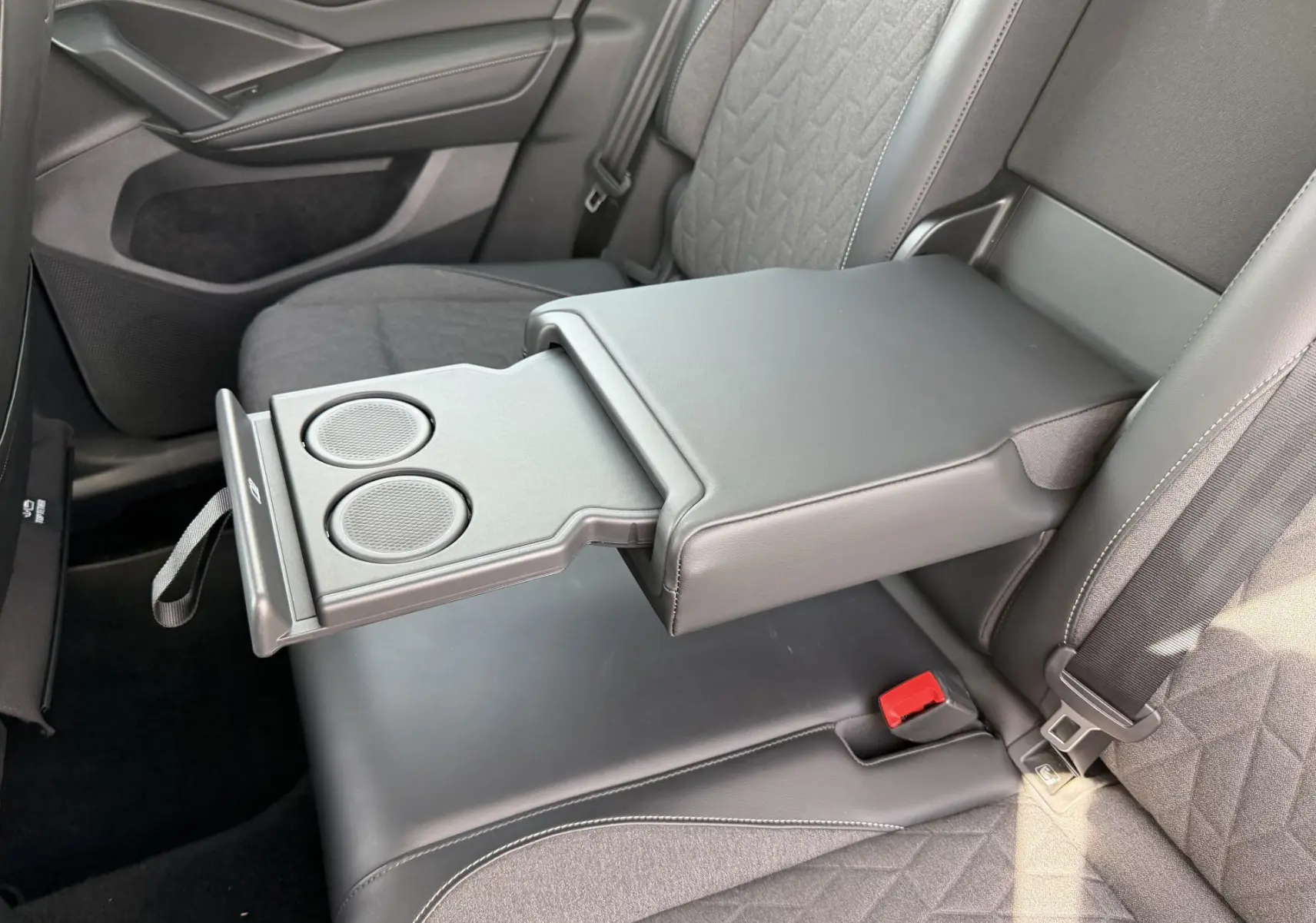 Vue rapprochée de l’accoudoir central arrière déployé avec porte-gobelets dans le Volkswagen Tiguan noir 2025.