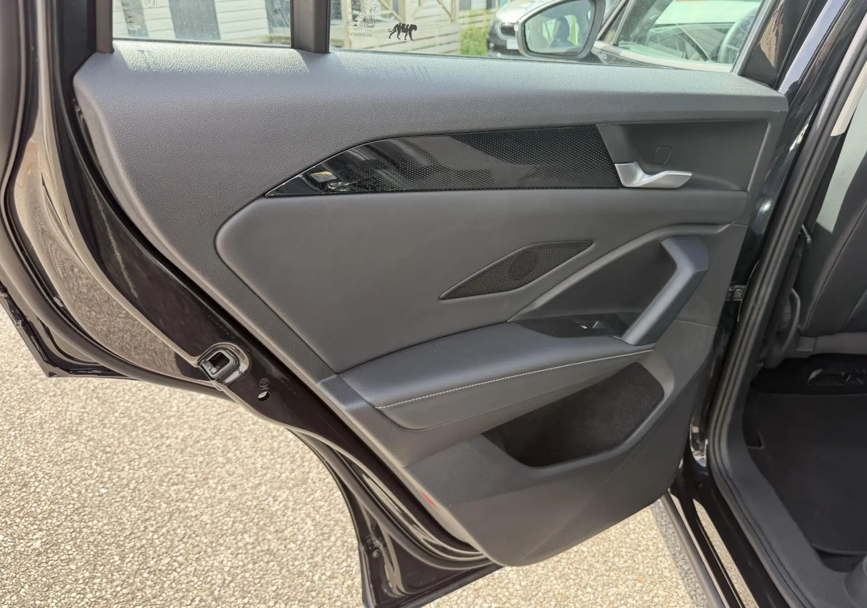 Vue de la porte arrière gauche ouverte du Volkswagen Tiguan noir, montrant les finitions intérieures en cuir et inserts noirs brillants.
