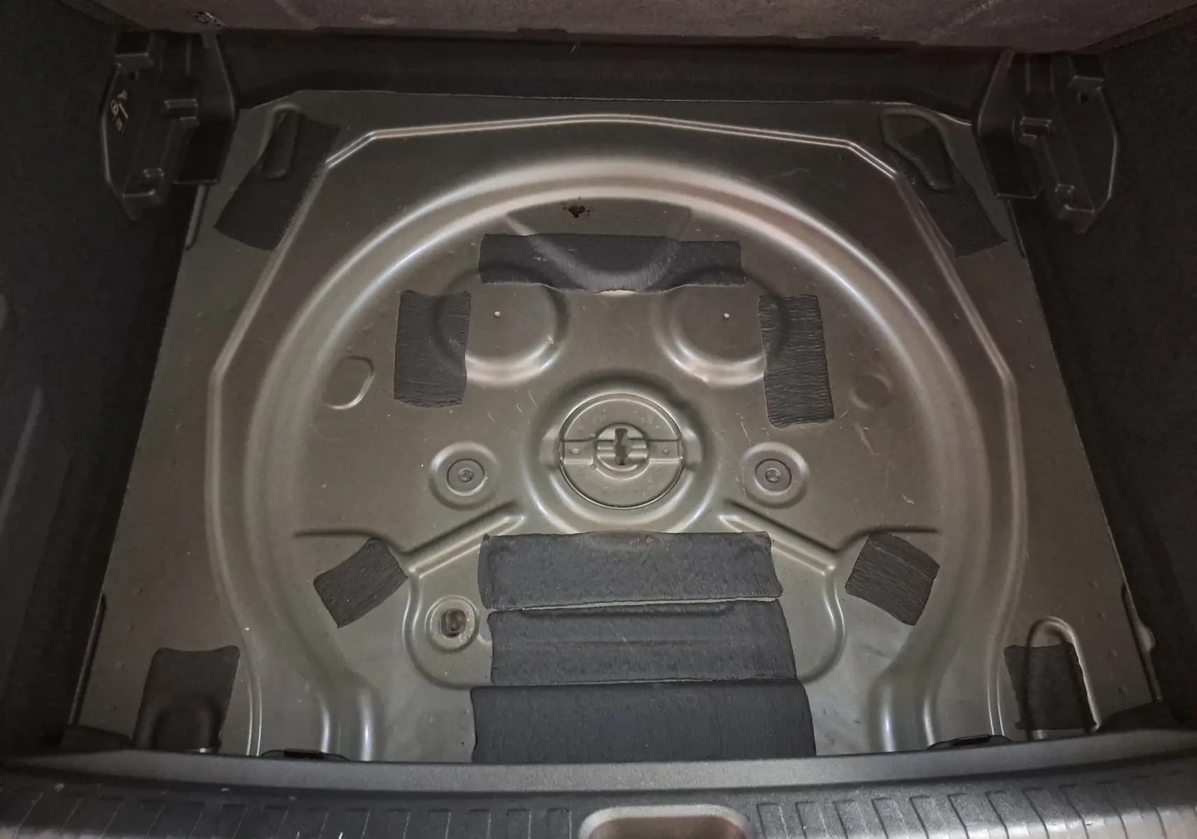 Vue plongeante sur le compartiment de roue de secours vide d'une CUPRA TERRAMAR 2025, gris Timanfaya.