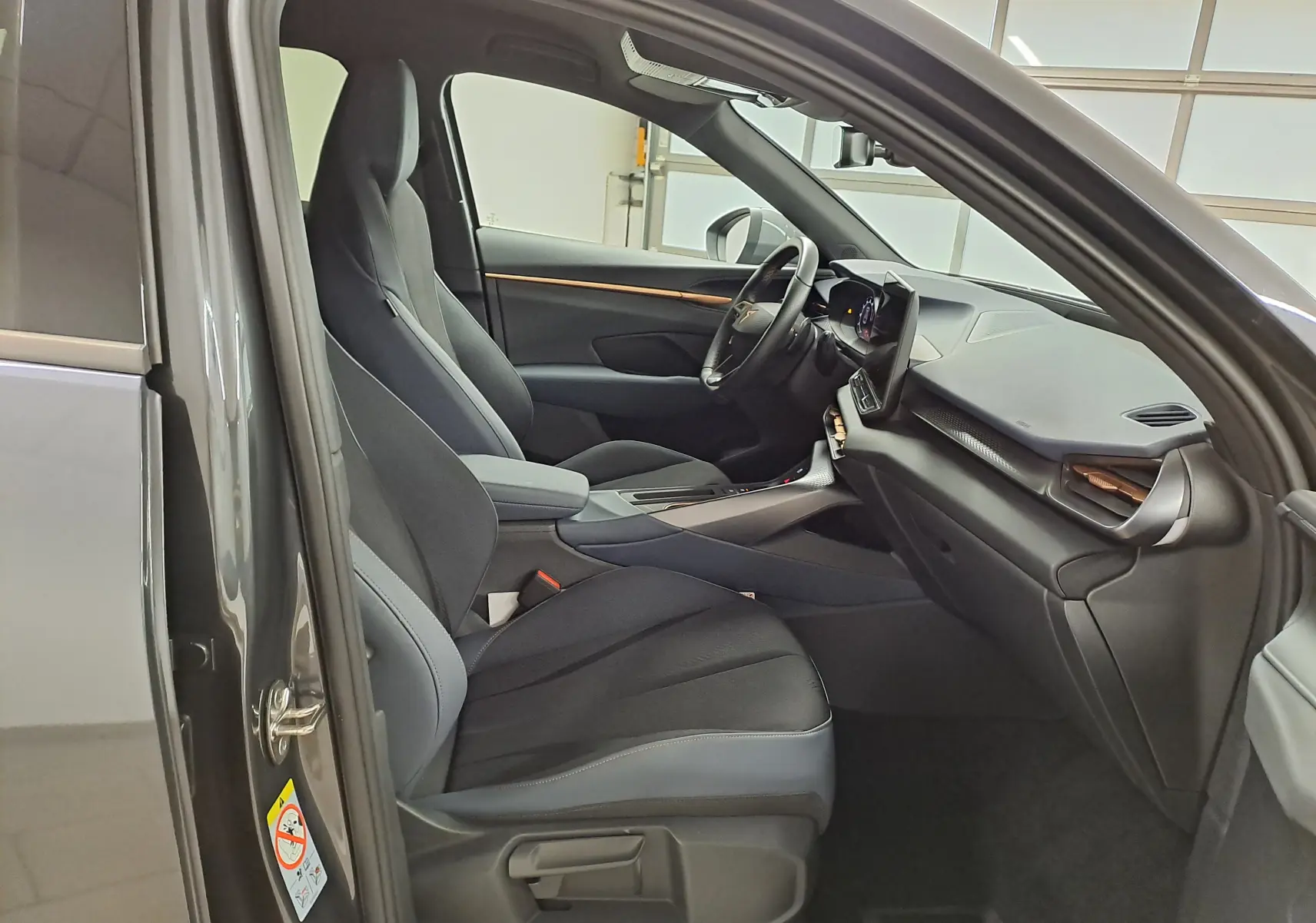 Vue intérieure côté conducteur du CUPRA TERRAMAR 2025, sièges noirs et tableau de bord moderne avec écran tactile.