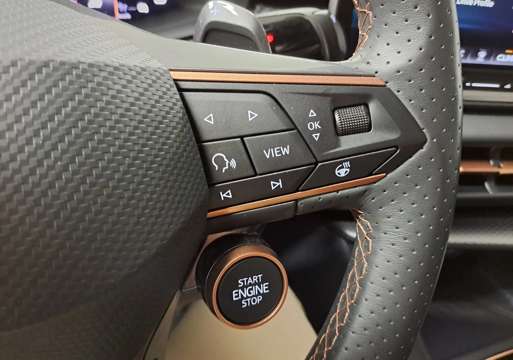 Gros plan sur le volant perforé noir avec surpiqûres cuivrées et bouton Start Engine Stop du CUPRA TERRAMAR 2025.