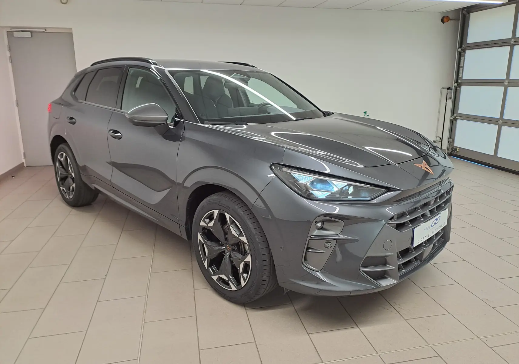 Vue 3/4 avant droit d'une CUPRA TERRAMAR gris Timanfaya avec jantes 19'' Cosmic usinées en intérieur lumineux.