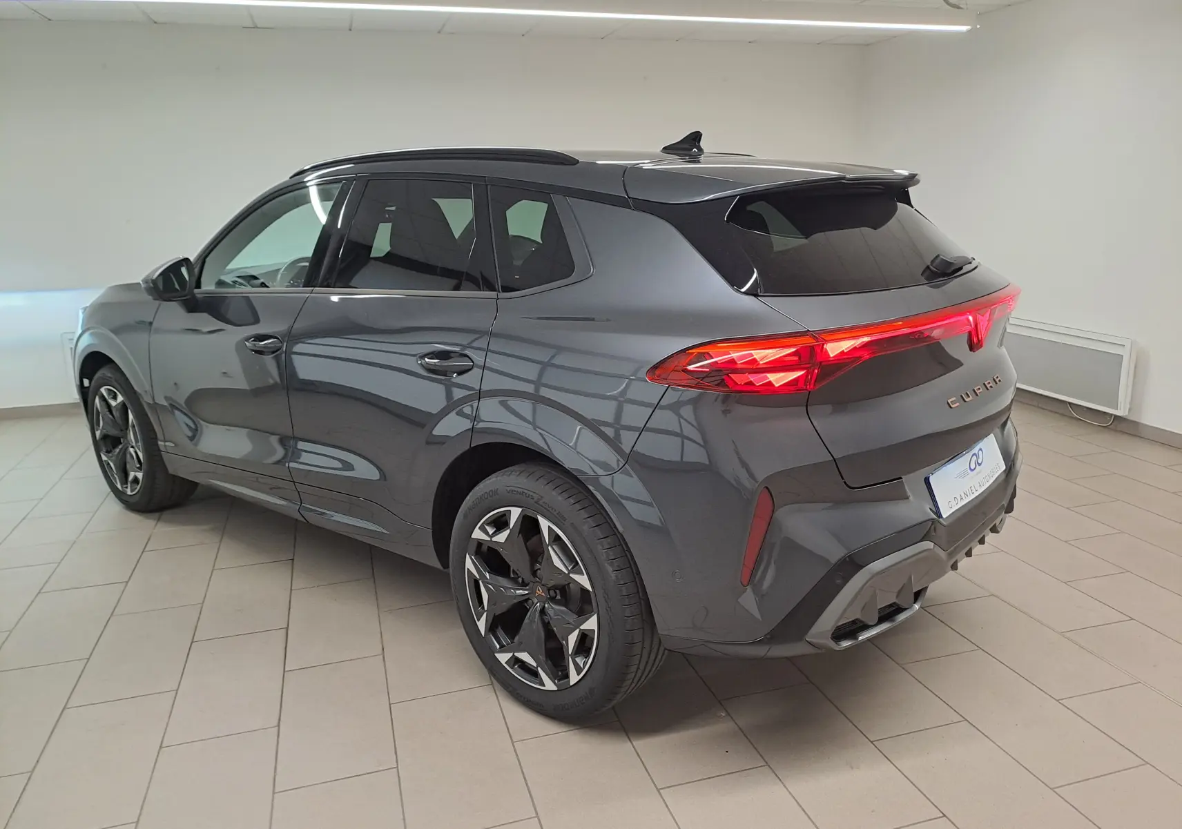 Vue 3/4 arrière droite du CUPRA TERRAMAR gris Timanfaya avec jantes 19'' Cosmic usinées et feux arrière allumés.