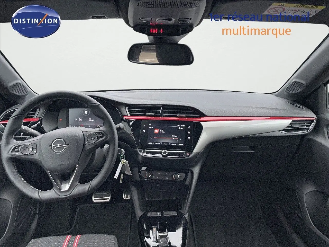 Intérieur de l'Opel Corsa blanc 2022 vu de face, tableau de bord noir avec bande rouge et écran tactile central.