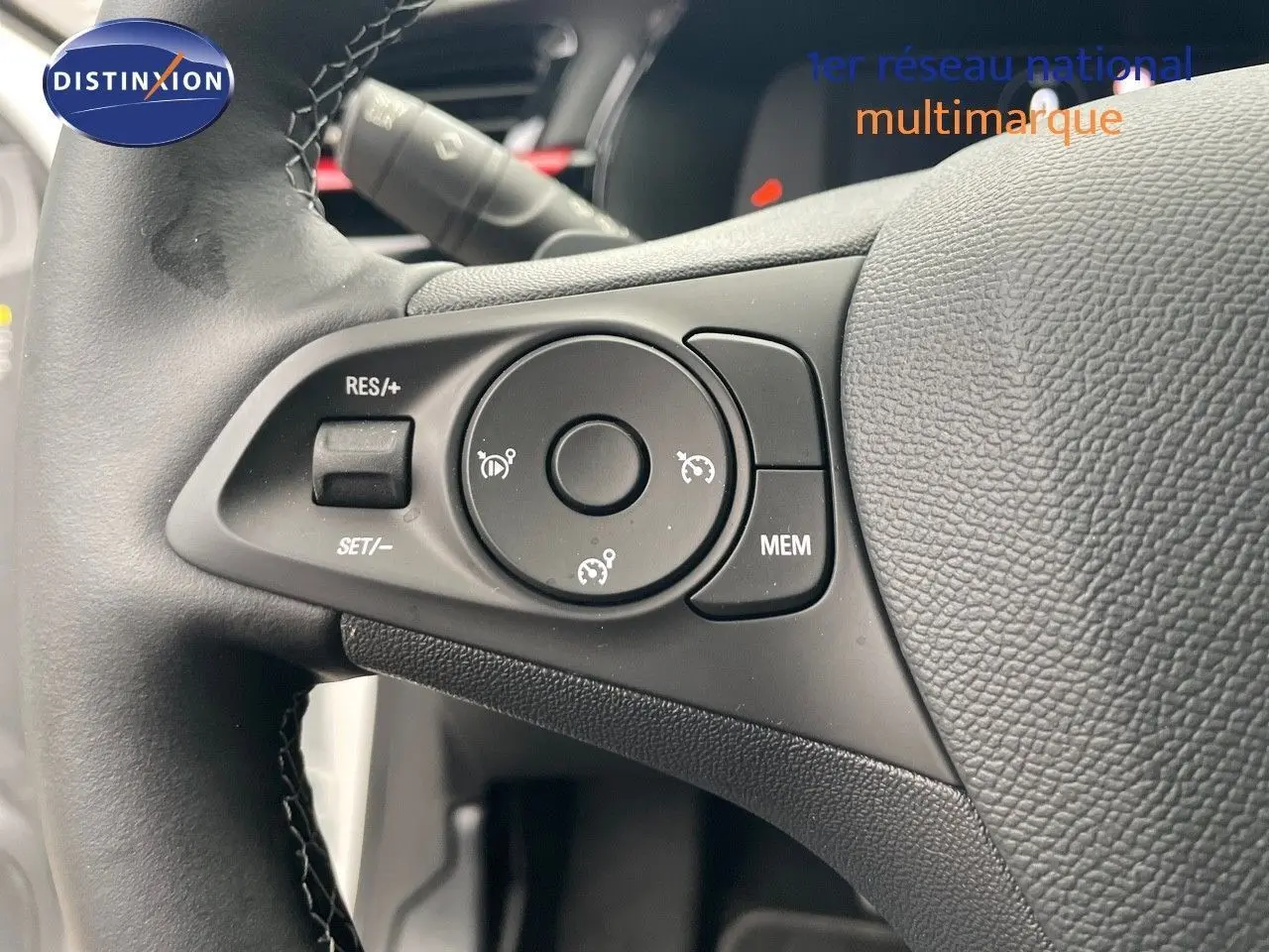 Gros plan sur les commandes du régulateur de vitesse au volant cuir noir d'une Opel Corsa blanche de 2022.