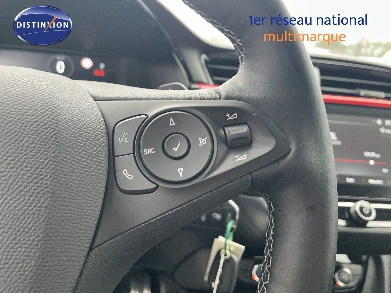 Gros plan sur le volant en cuir noir de l'Opel Corsa blanc, avec commandes audio intégrées et tableau de bord en arrière-plan.