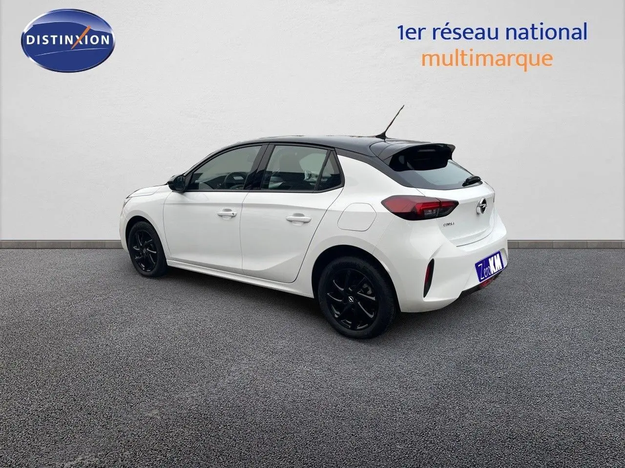 Opel Corsa blanc vue 3/4 arrière côté droit avec toit noir et jantes noires sur fond neutre.