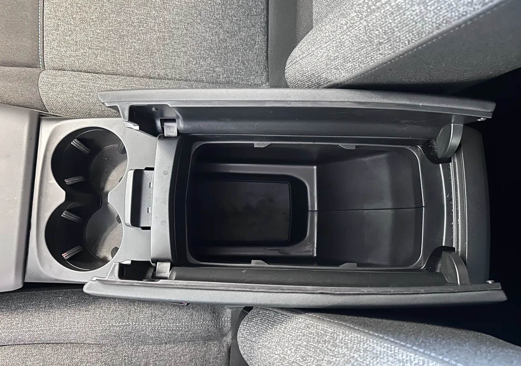 Vue plongeante sur le rangement central ouvert et porte-gobelets du Citroën C5 Aircross 2024 en tissu gris.