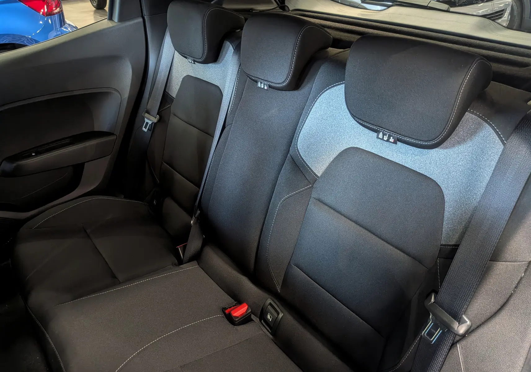 Vue intérieure des sièges arrière en tissu noir et gris de la Renault Clio V Blue dCi 100 Evolution, avec ceintures visibles.