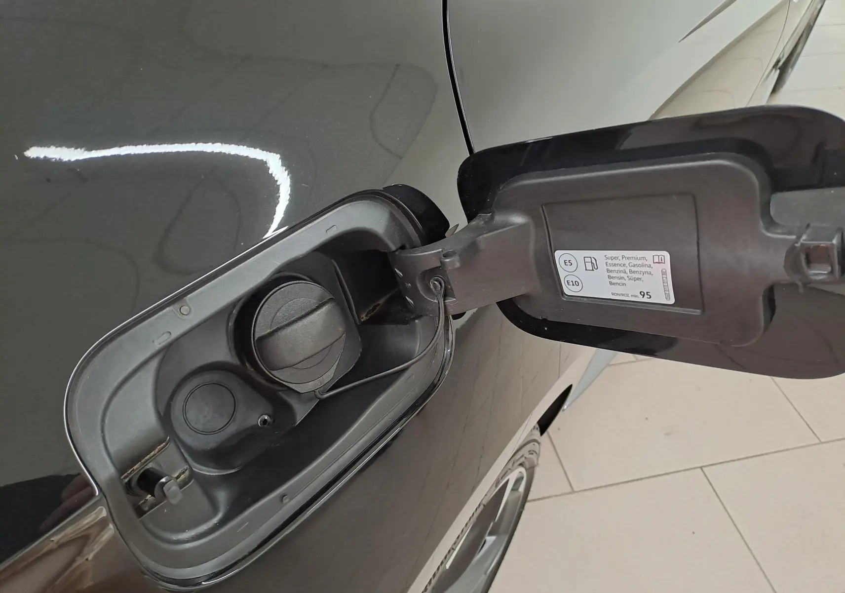 Gros plan sur la trappe à carburant ouverte côté gauche d'une CUPRA Leon Noir Minuit, essence, avec bouchon noir.