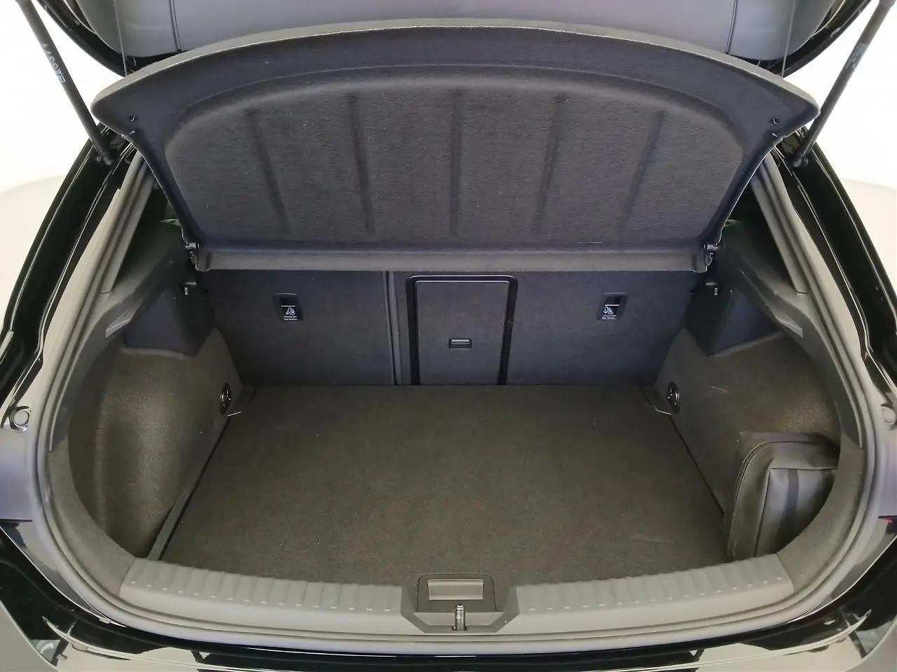 Coffre ouvert vu de l'arrière d'une CUPRA Leon Noir Minuit avec intérieur de coffre spacieux et habillage sombre.